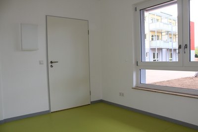 Eingangsbereich der Wohnung mit heller Wand und grünen Boden