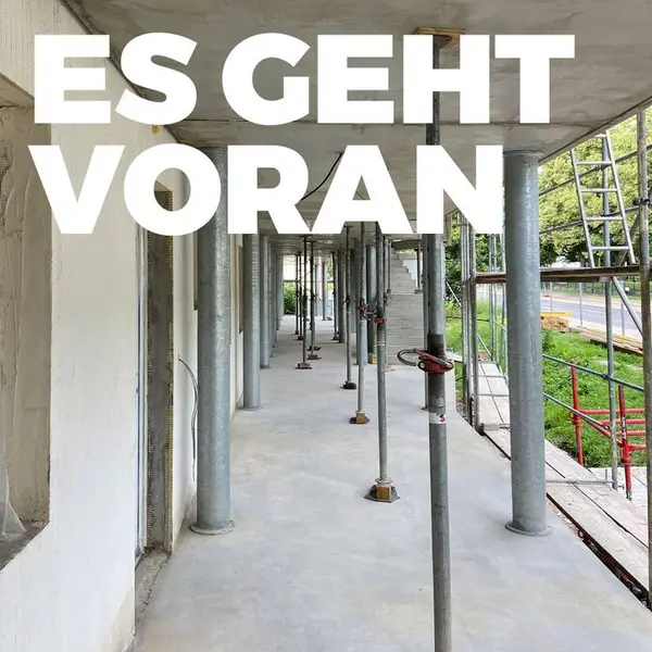 Baustelle mit Stützen und Gerüsten, Text: "Es geht voran"